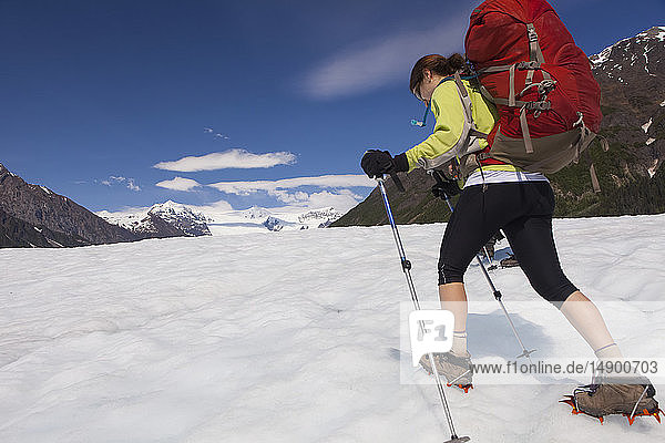 Frau  die im Sommer mit dem Rucksack über den Root-Gletscher mit Steigeisen zum Donoho Peak wandert  Wrangell Mountains  Wrangell-St. Elias National Park  Süd-Zentral-Alaska; Kennicott  Alaska  Vereinigte Staaten von Amerika