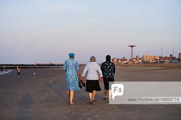 Orthodoxe jüdische Frauen spazieren am Strand von Coney Island nach Sonnenaufgang; Coney Island  New York  Vereinigte Staaten von Amerika