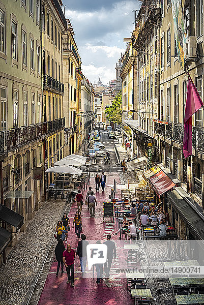 Fußgänger  die eine schmale Straße zwischen Gebäuden mit Restaurantterrassen und Ladenfronten in Bairro Alto  Lissabon  hinuntergehen; Lissabon  Portugal