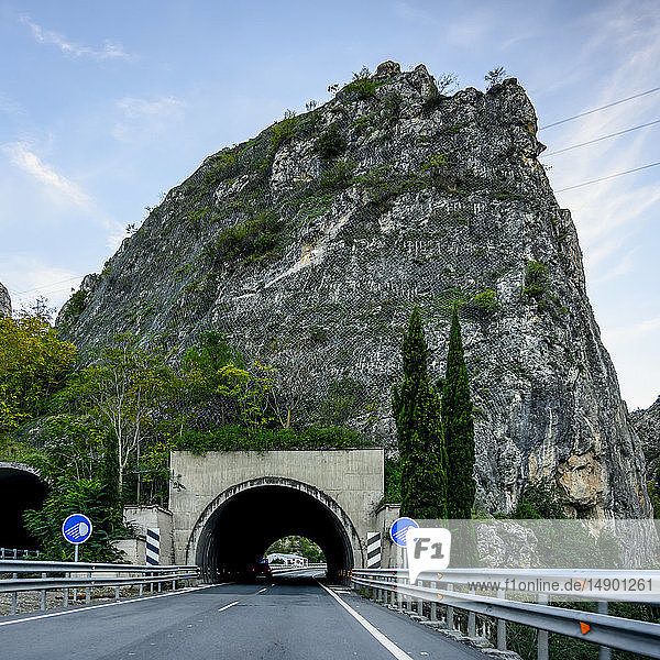 Eine Straße  die durch einen dunklen Tunnel führt  mit Schildern  die auf die empfohlene Verwendung von Scheinwerfern hinweisen; Campillo de Arenas  Provinz Jaen  Spanien