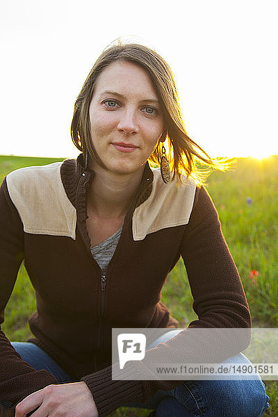 Portrait of a young woman in a meadow with wildflowers at sunset; Waco Texas United States of America