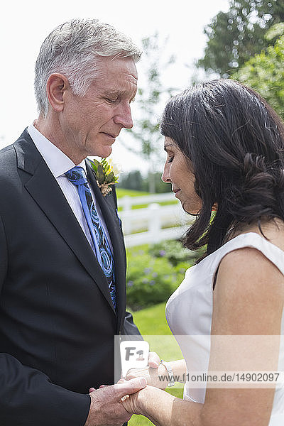 A bride and groom holding hands and praying together; Langley  British Columbia  Canada