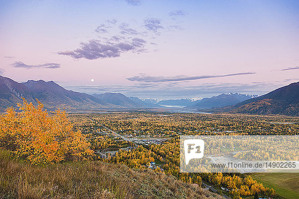 Blick auf den Mond  der über Palmer und dem Knik River von der Butte aus aufgeht  im Hintergrund die Chugach Mountains während der Dämmerung an einem klaren Abend  Süd-Zentral-Alaska; Palmer  Alaska  Vereinigte Staaten von Amerika
