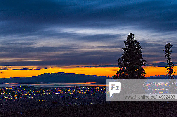 The setting sun over Alaska's Mount Susitna  locally known as 'The Sleeping Lady'  with the Cook Inlet and the city of Anchorage in the foreground as seen from Chugach State Park; Anchorage  Alaska  United States of America