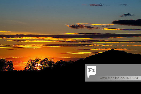 Silhouettierter Hügel und Bäume während eines glühenden Sonnenuntergangs; Waterloo  Quebec  Kanada