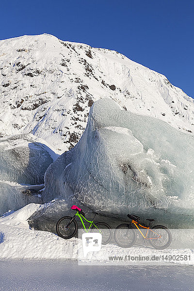 Fatbikes  907 fat tire bike und Fatback fat tire bike  ruhen gegen einen riesigen Eisberg im Winter auf dem Portage Lake  Chugach National Forest; Portage  Alaska  Vereinigte Staaten von Amerika