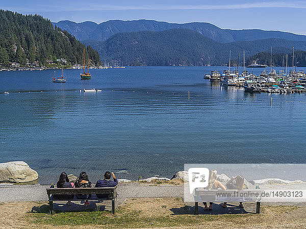 Menschen sitzen auf Bänken und blicken auf den Hafen und die Küstenlinie von Deep Cove  North Vancouver; Vancouver  British Columbia  Kanada