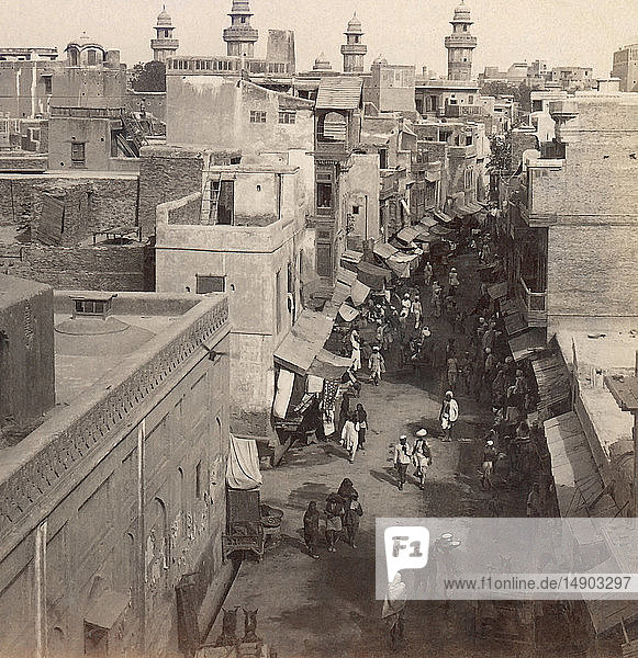 Viktorianische Stereokarte von ca. 1900  historisches Gesellschaftsbild. Blick nach Südwesten durch eine Straße mit Geschäften und Häusern zur Vizir Khan Moschee; Lahore  Punjab  Pakistan