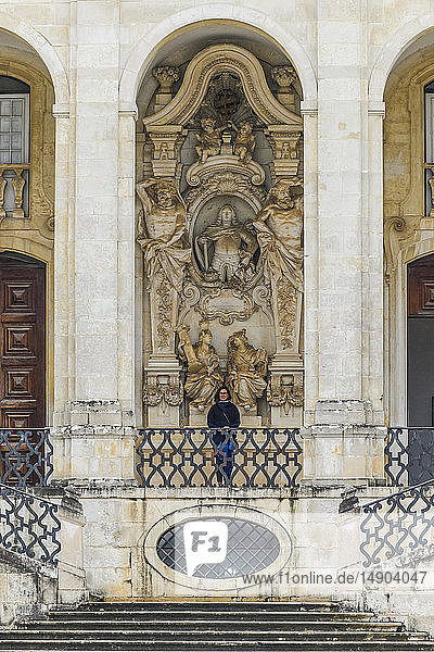 Weibliche Touristin steht vor einem verschnörkelten Gebäude im Innenhof der Universität von Coimbra; Coimbra  Bezirk Coimbra  Portugal