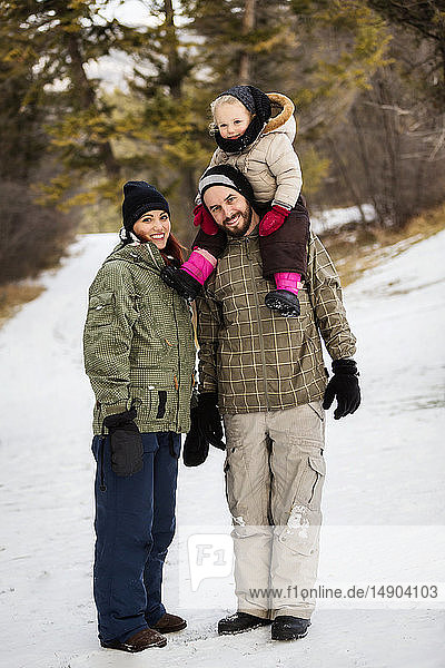 A young family hiking outdoors with their young daughter during a winter family outing: Fairmont  British Columbia  Canada