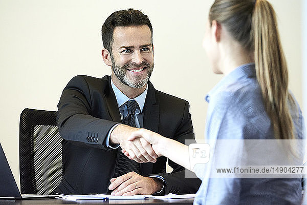 Businessman shaking hands with businesswoman in office