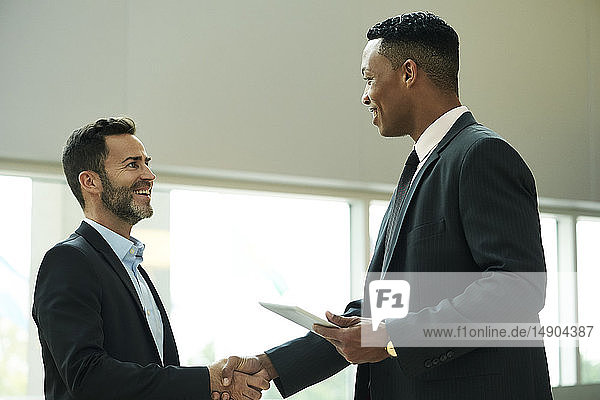 Businessmen shaking hands in office lobby