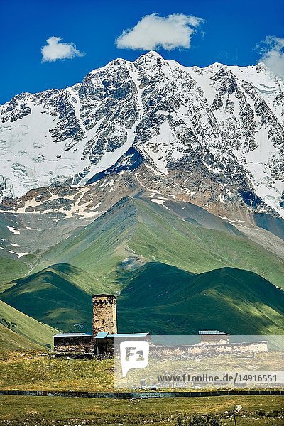 The medieval Georgian Orthodox St George Church “JGRag with mount Shkhara (5193m) behind Ushguli Upper Svaneti Samegrelo-Zemo Svaneti Mestia Georgia. At 2 200 m (7217 ft) above sea level in the Caucasus mountains St George Church is one of the highest in Europe. Mount Shkhara is the highest mountain in the Caucasus range.