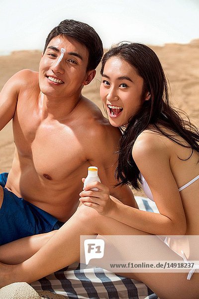 Das junge Paar am Strand Sonnenschutzmittel