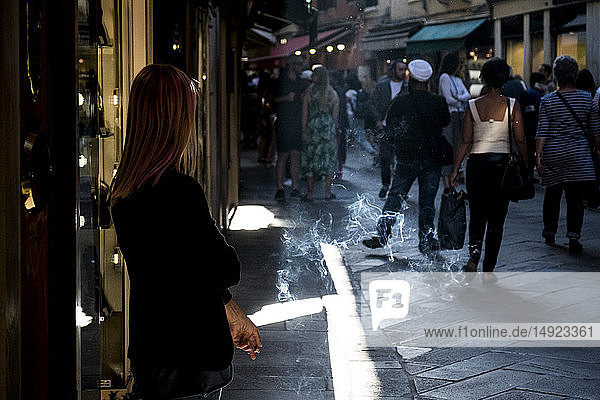 Frau steht in einer engen Straße in Venedig  Venetien  Italien  und raucht eine Zigarette.