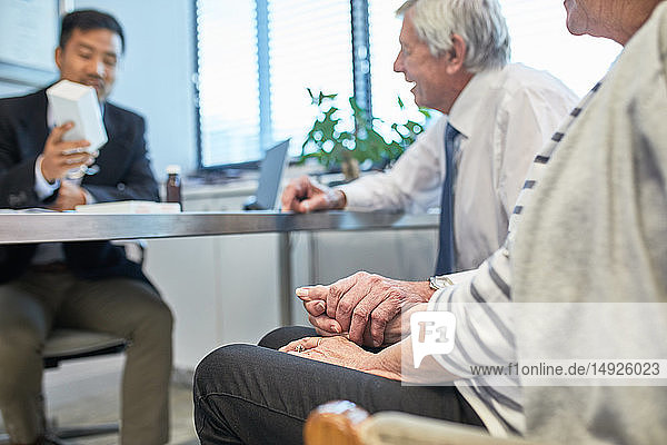 Doctor talking with senior couple in clinic doctors office