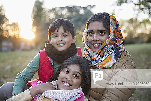 Portrait happy Muslim mother in hijab with children in autumn park