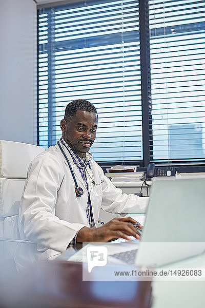 Männlicher Arzt arbeitet am Laptop in einer Arztpraxis