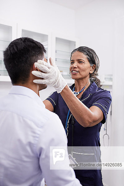 Eine Ärztin untersucht einen männlichen Patienten im Untersuchungsraum einer Klinik