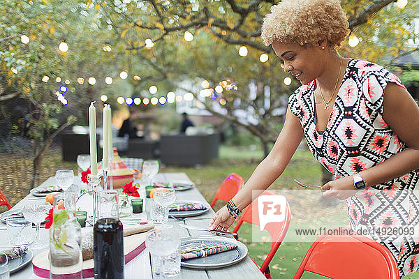 Frau deckt Tisch für Abendessen Gartenparty