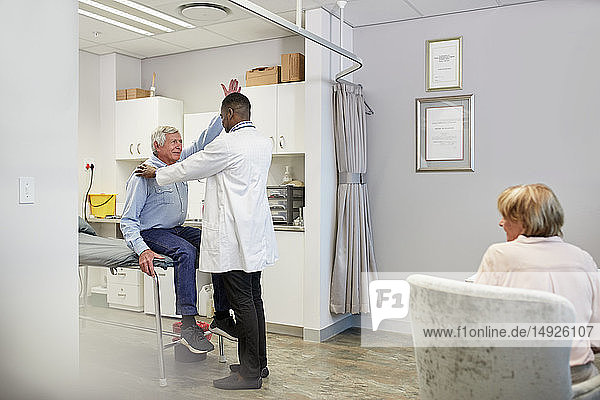 Doctor examining senior male patient in examination room