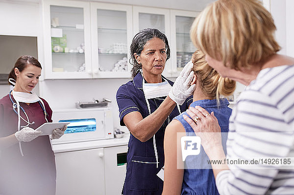 Female pediatrician examining girl patient in clinic examination room