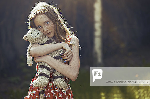 Portrait serene tween girl with stuffed animal in park