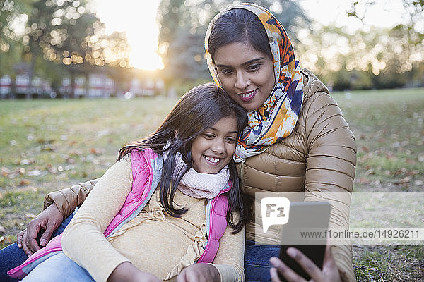 Muslimische Mutter im Hidschab macht Selfie mit Tochter im Herbstpark