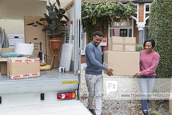 Ehepaar zieht aus dem Haus aus und trägt Kisten zum Umzugswagen