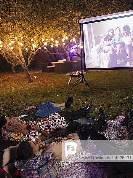 Freunde entspannen sich  schauen einen Film auf der Projektionsfläche im Hinterhof