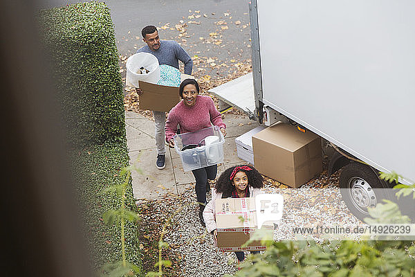 Familie zieht in ein neues Haus ein  trägt Kisten aus dem Umzugswagen