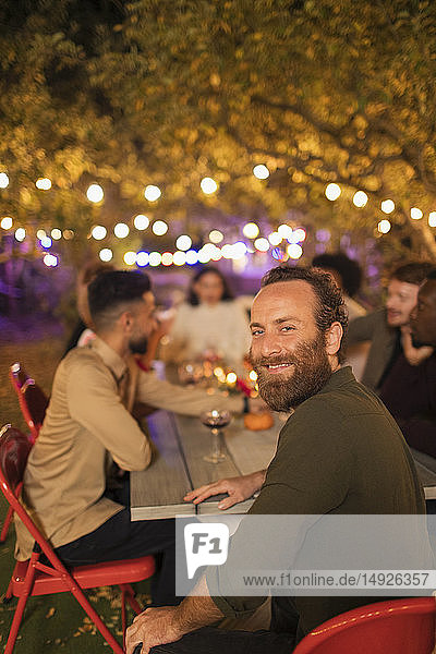 Porträt eines glücklichen Mannes beim Abendessen auf einer Gartenparty