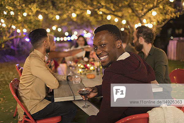 Portrait smiling man drinking wine  enjoying dinner garden party