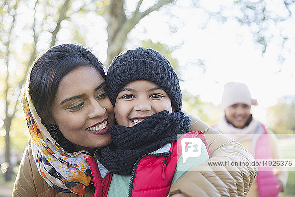 Portrait happy Muslim mother in hijab hugging son in autumn park