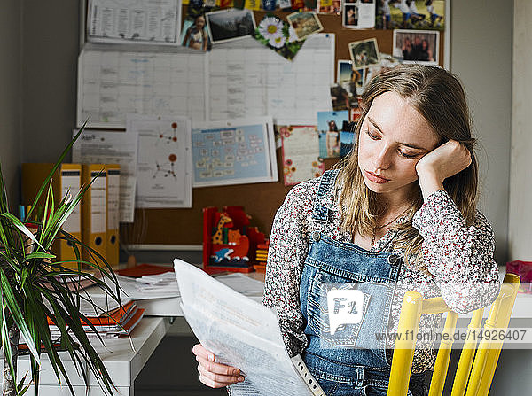 Konzentrierte junge Frau arbeitet im Büro zu Hause und liest Papierkram