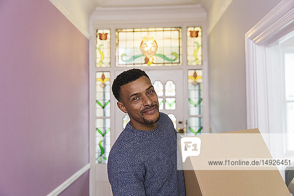 Porträt eines lächelnden  zuversichtlichen Mannes beim Einzug in ein neues Haus