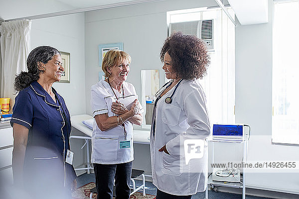 Female doctor and nurses talking in clinic examination room