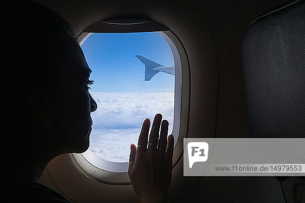 Frau reist im Flugzeug und schaut aus dem Fenster
