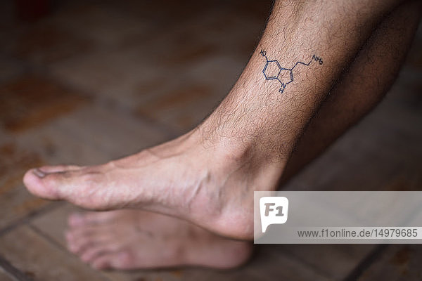 Tattoo of molecule serotonin on shin of man