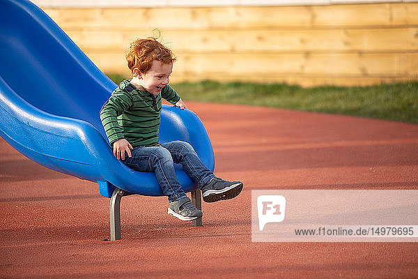 Boy playing on slide in playground