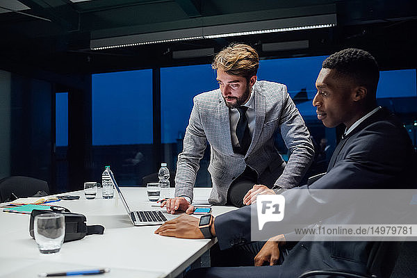 Geschäftsleute schauen während der Sitzung am Konferenztisch auf den Laptop