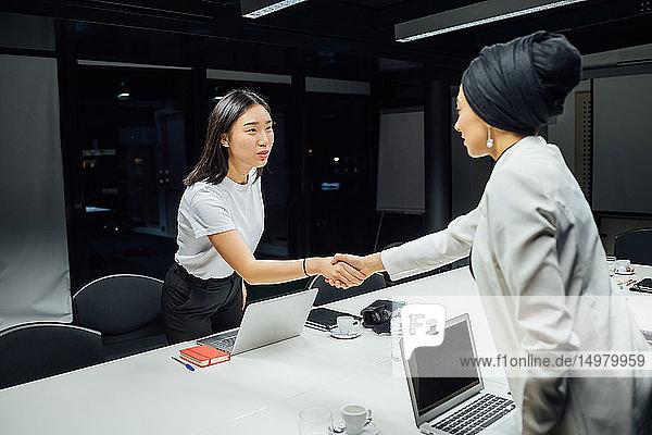 Geschäftsfrauen schütteln Hände über Konferenztisch