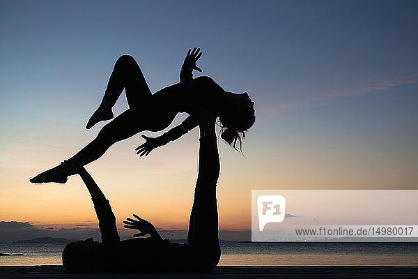Frauen praktizieren Akro-Yoga am Meer