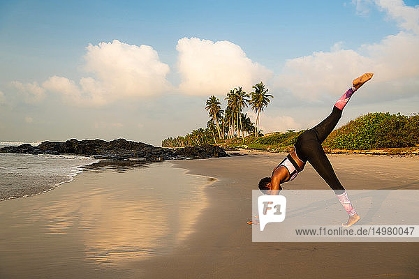 Woman practising yoga on beach