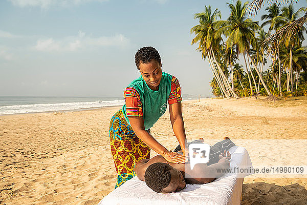 Woman massaging man on beach