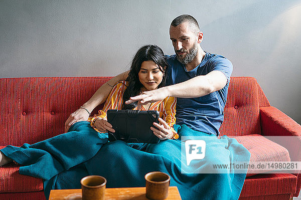 Hipster-Paar mit digitalem Tablett auf dem Sofa