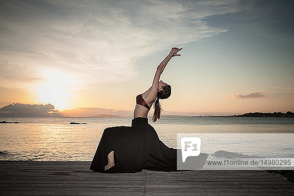 Frau praktiziert Yoga am Meer