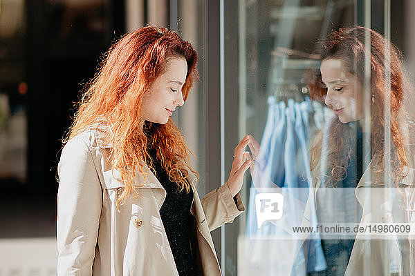 Woman looking into window of fashion boutique