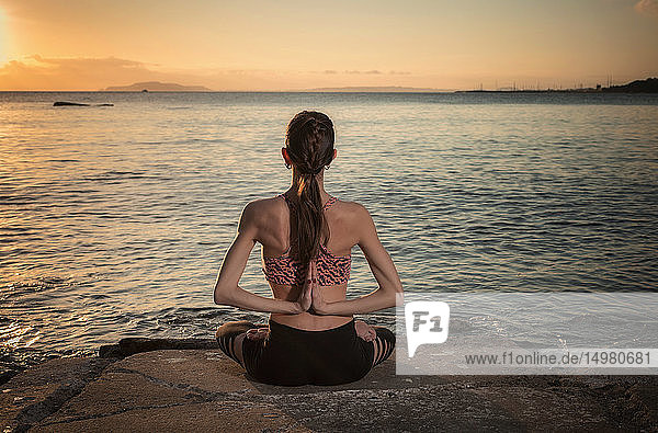 Woman practising yoga at seaside