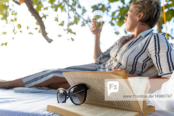 Frau liest Buch auf Schaukelbett am Strand  Insel Ginto  Linapacan  Philippinen
